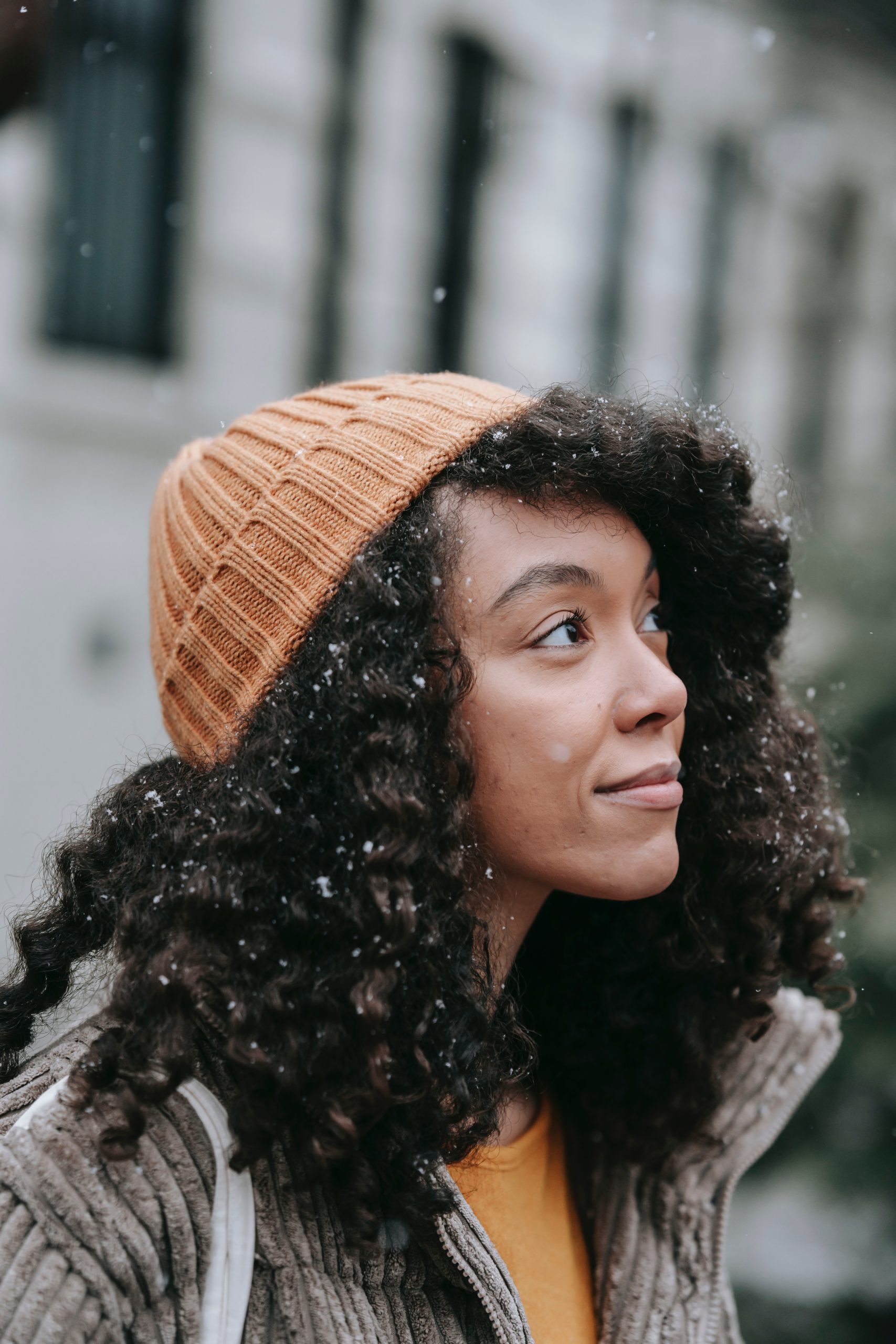 contemplative-ethnic-woman-with-curly-hair-in-snowfall